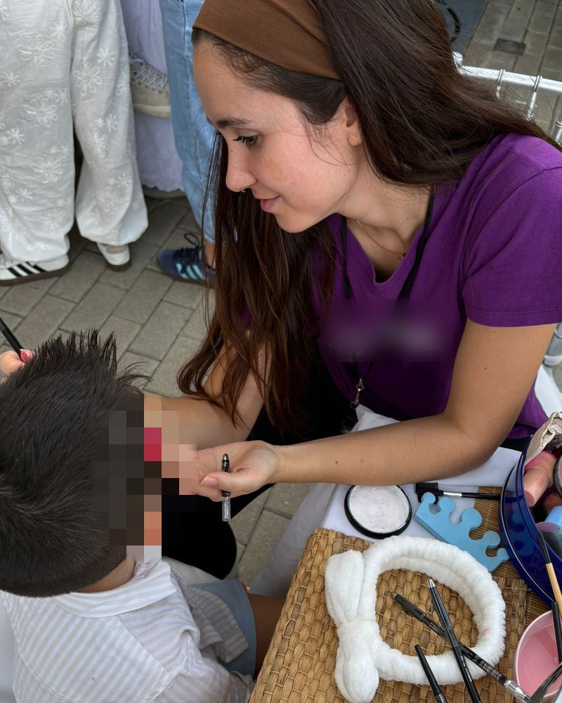 Elisa pintando la cara a un niño en un evento infantil
